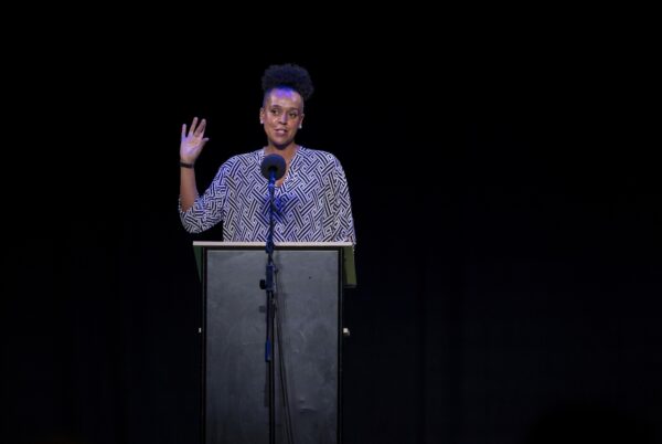 A lady speaking into a microphone on a stage.