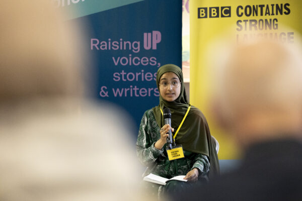 A woman in a hijab talks into a microphone.