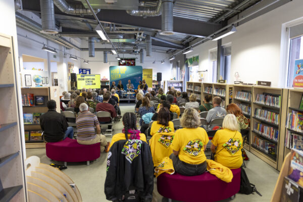 A room full of people watch five poets on stage.