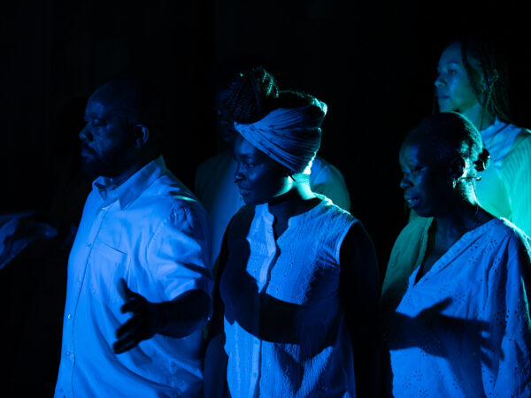 A trio of people, lit by blue stage lights.