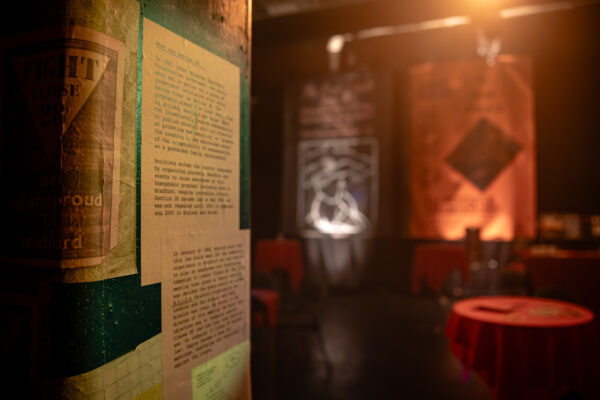 A wall and pillar is decorated with historical posters and signage.