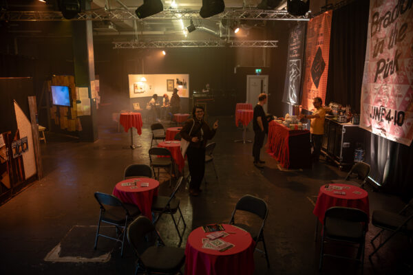 People explore the exhibition - located in a basement space - with tables down the middle.
