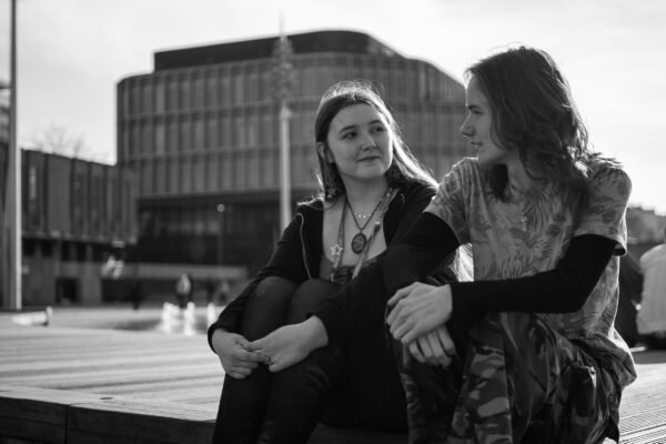Two young people sat looking at each other in City Park, in black and white