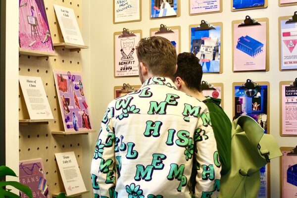 Two people study a wall covered in brightly coloured artwork.