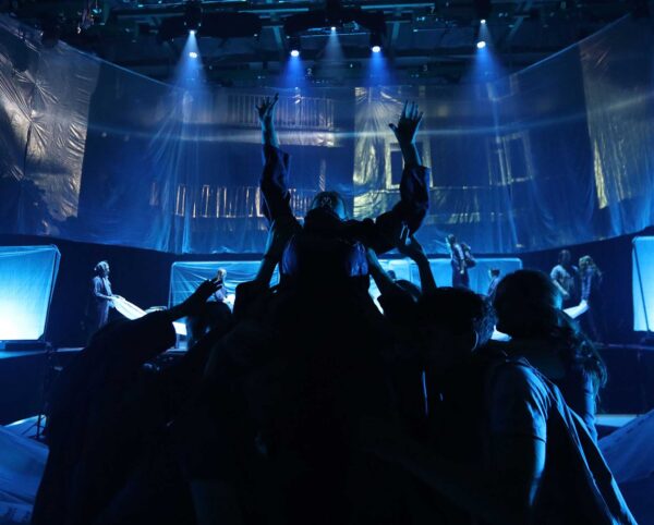 An image from a stage performance, with dancers in silhouette lit in blue light.
