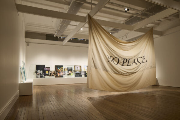 Rene Matić's installation at Cartwright Hall Art Gallery. In the centre of the room is a large banner that reads 'No Place' on one side.