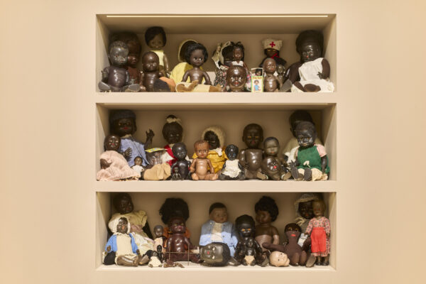 Three shelves with small dolls. The dolls are all black or brown skinned.