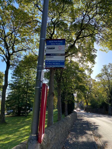A bus stop sign. The blue and white sign is on a lamp post, with a red frame underneath it.