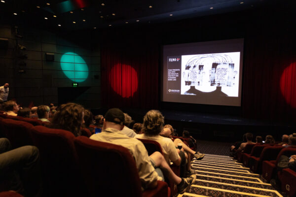 people sat down in a cinema looking at the big screen
