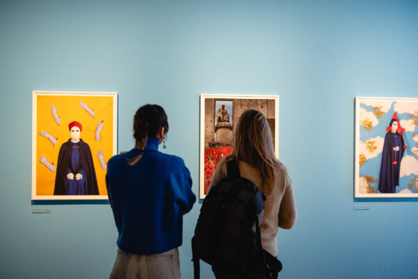 The back of two girls who are looking at pieces of art in a gallery.