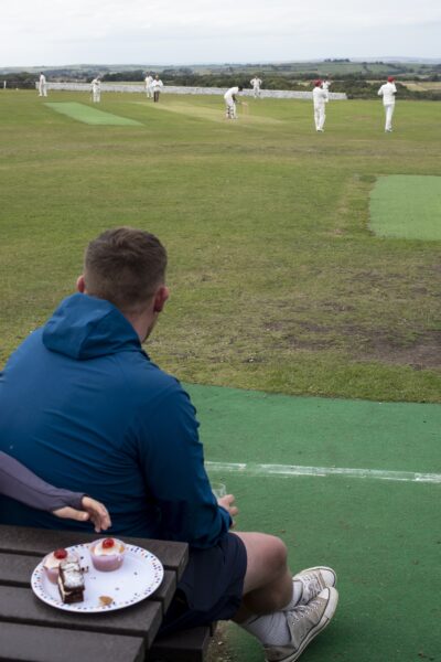 People sat outside watching the cricket.