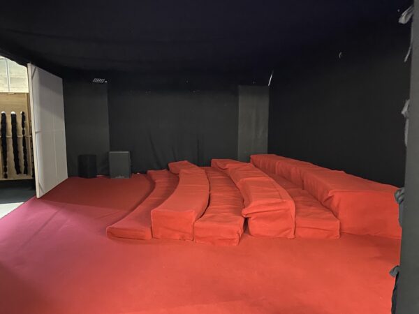 A curved steel frame with bright orange cloth holders for shoes, and some ear defenders.