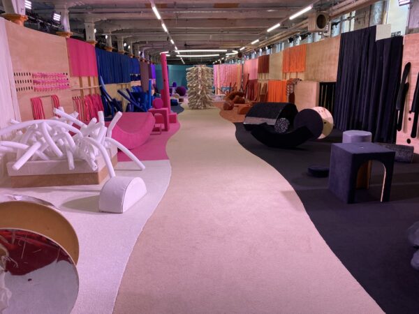 A collection of recycled, fun things, separated into colours. A central path of beige carpet creating clear space between.