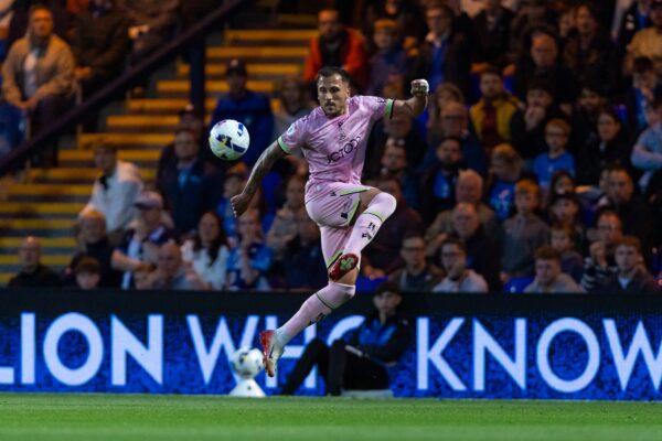 Bradford City footballer in a pink kit, mid air kicking the football