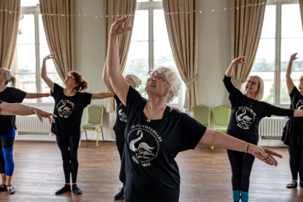older ladies dancing, posing with their feet together, with one arm up and one arm out