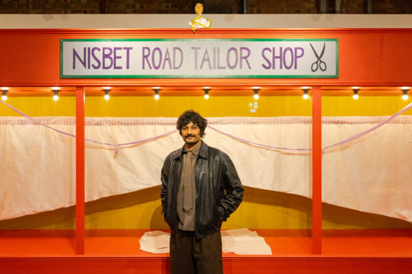 Artist, Zain Ali, standing in front of 'Nisbet Road Tailor Shop' in Loading Bay