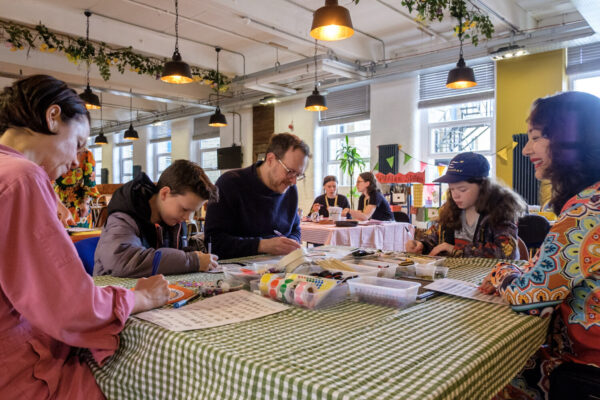 Adults and children sat down drawing and doign crafts together at a table