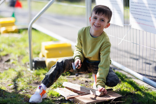 A boy in a green jumper works with tools.
