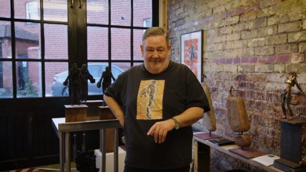 Jonny Vegas stands in his studio wearing a black t shirt.