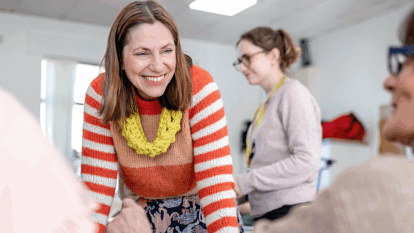 A woman smiling as she leans over a table