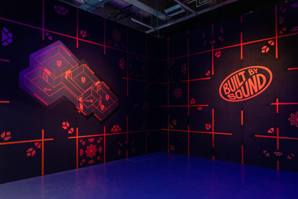 Glowing orange drawings on walls in room one of Built by Sound in the basement of Loading Bay.