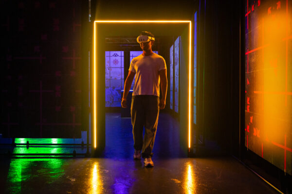A man walking through a glowing orange doorway with a VR headset on.