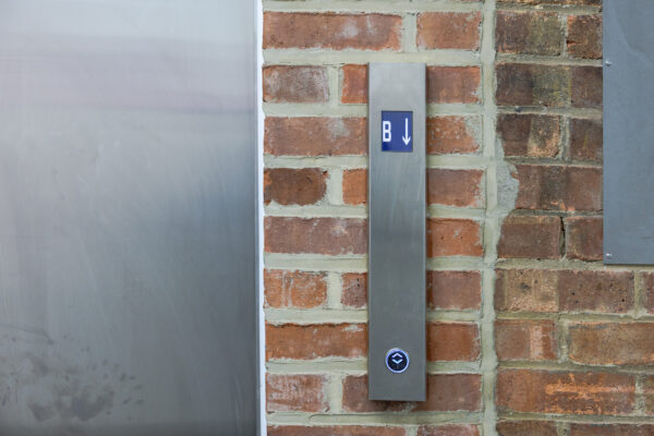 The button outside of the elevator in the basement of Loading Bay.