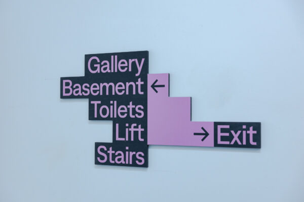 Sign inside Loading Bay, which lists gallery, basement, toilets, lift and stairs on right side. It lists exit on the right side.