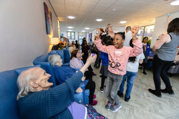 An elderly lady playing and dancing with a young girl