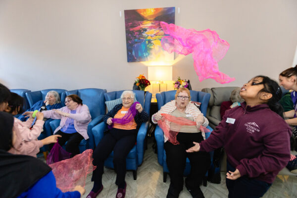 Young children playing about having fun in an elderly home with the residents