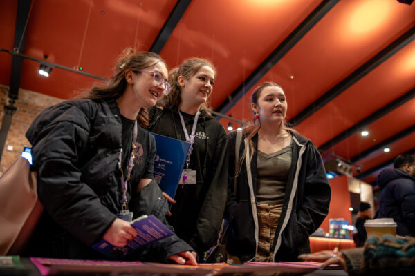 Young people all smiling, engaging with a careers stall