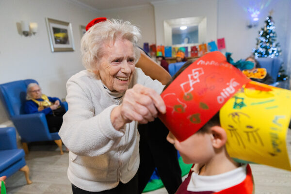 An elderly lady playing dress up and dancing with a young boy