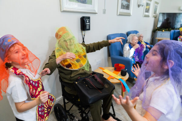 An elderly lady playing dress up and dancing with a young girls