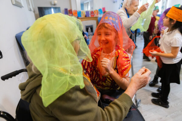 An elderly lady playing dress up and dancing with a young girl