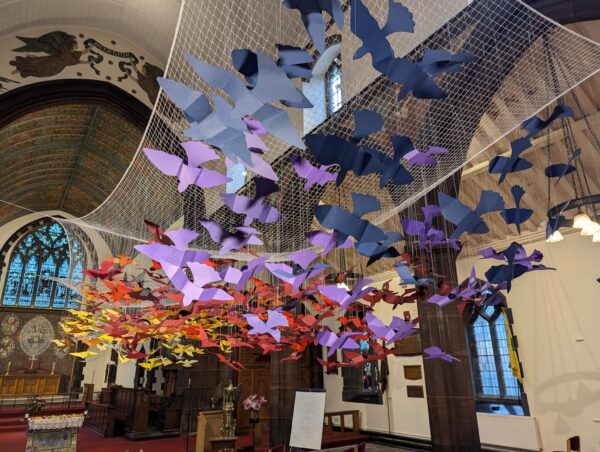 Colourful paper birds hanging from a cathedrals roof
