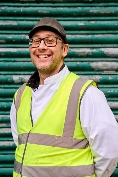 A man in glasses and a hivis smiles.