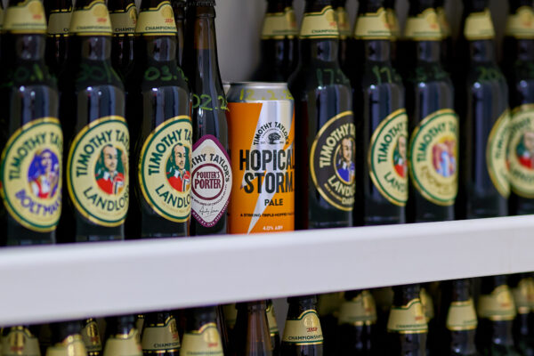 Glass bottles beer on a shelf with a can of beer in the centre.