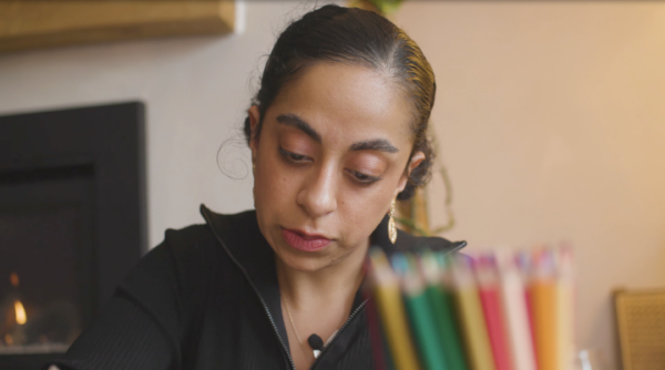 A woman looks down at the paper as she draws.